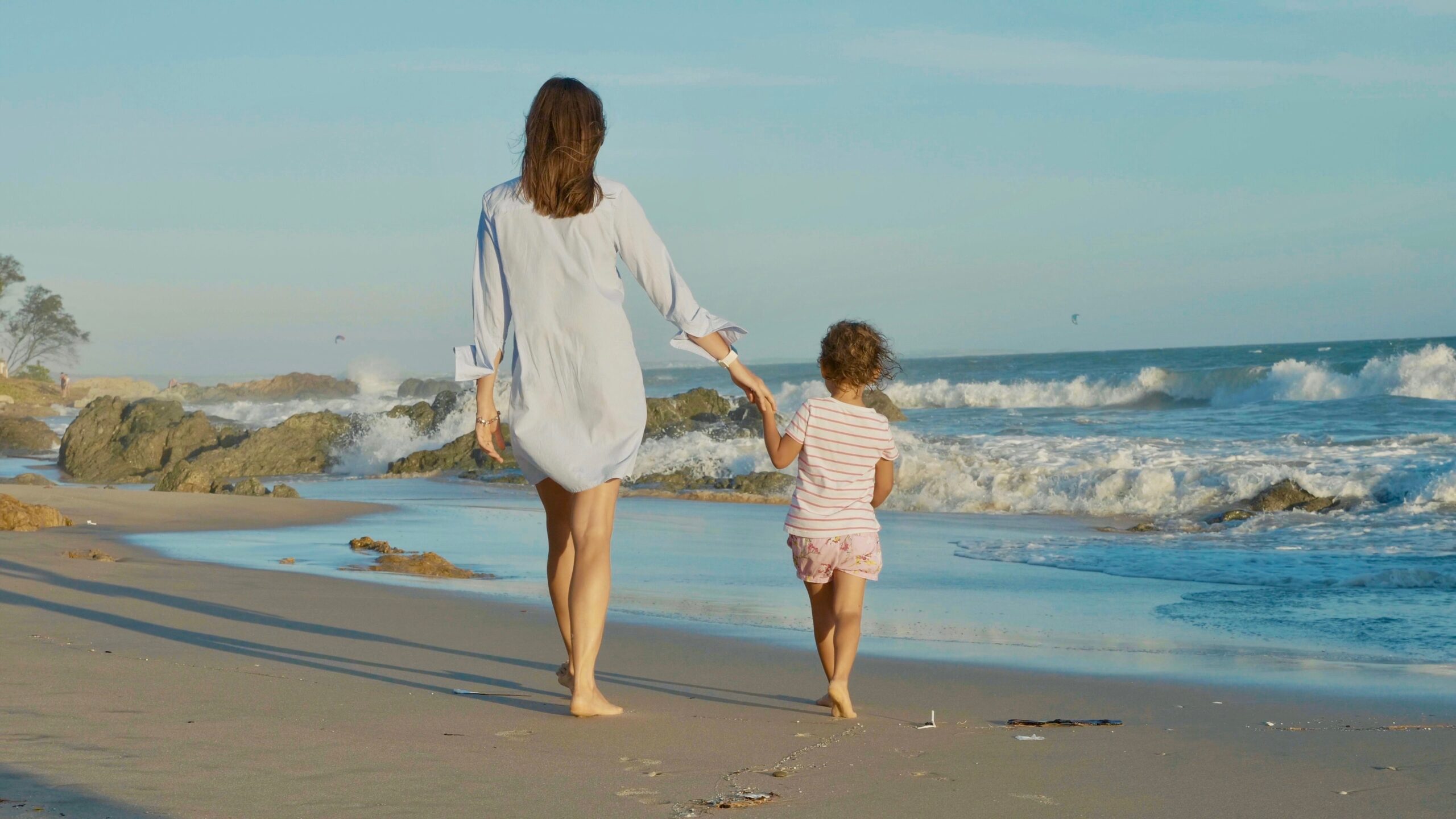 mother and child holding hands at the beach